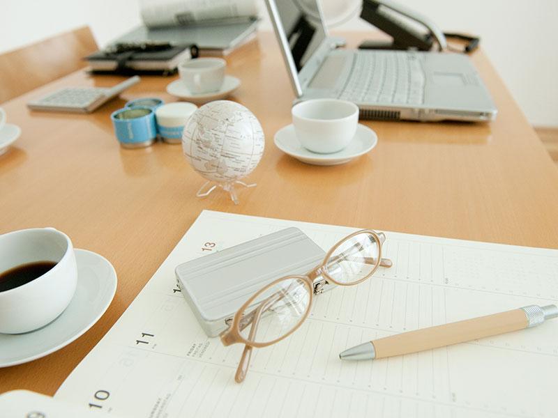 Office with on diary, glasses and coffee cup on desk