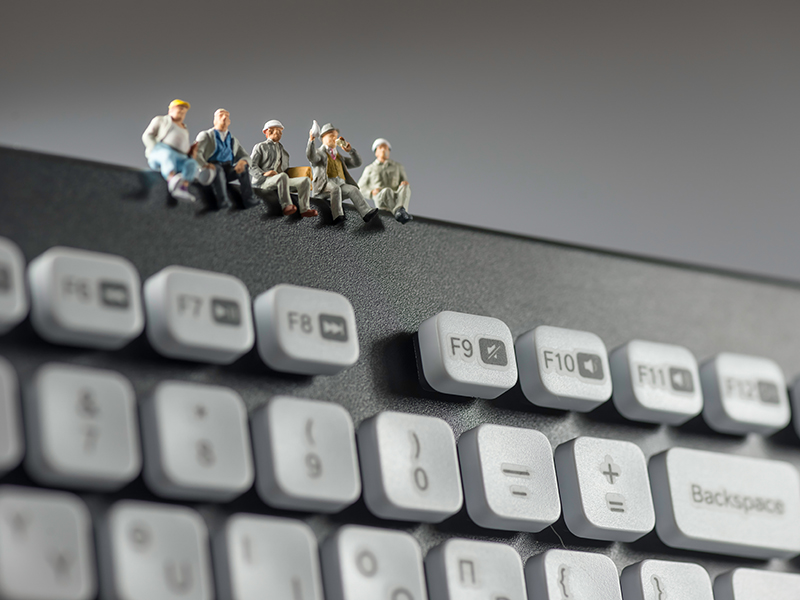 Miniature workers sitting on top of keyboard. Technology concept. Macro photo