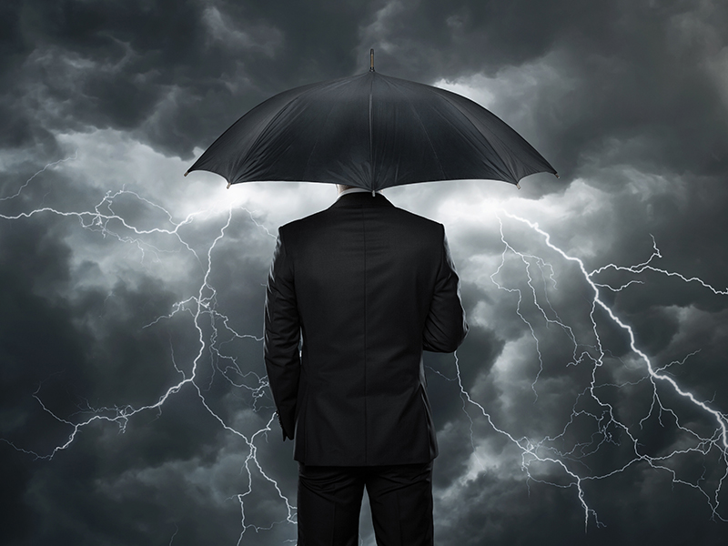 Trouble ahead, Businessman with umbrella standing in front of stormy clouds