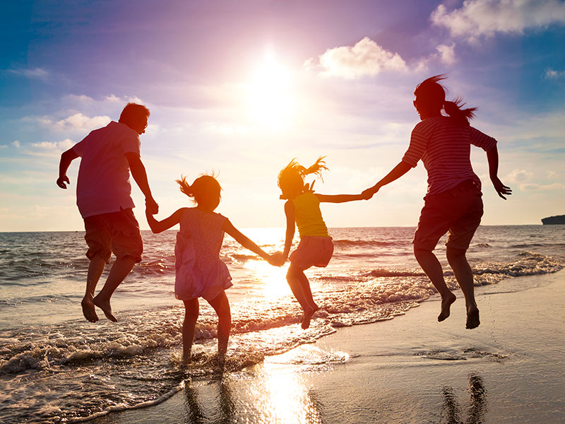 Happy family jumping together on the beach