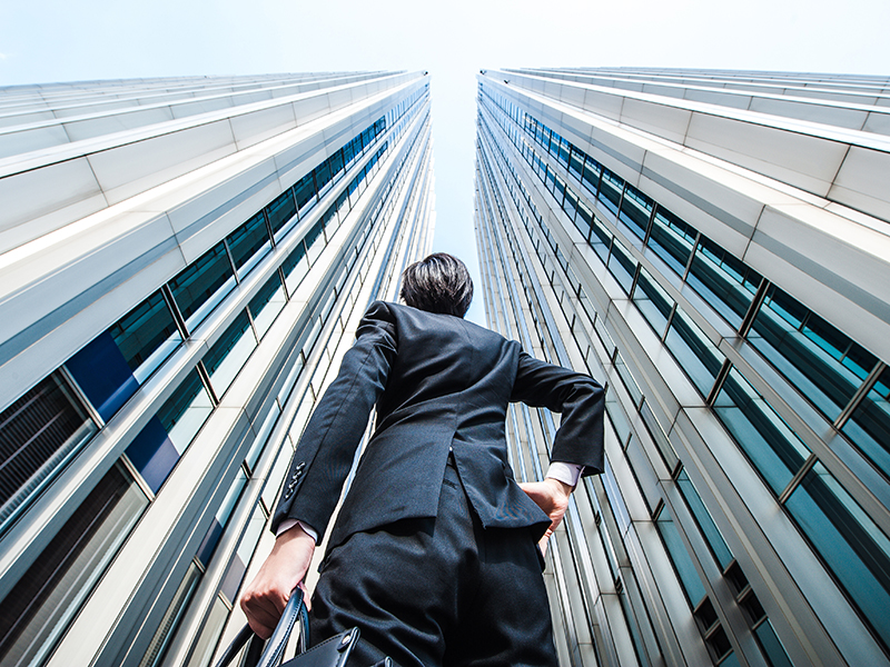 Businessman looking up at the high building, low angle