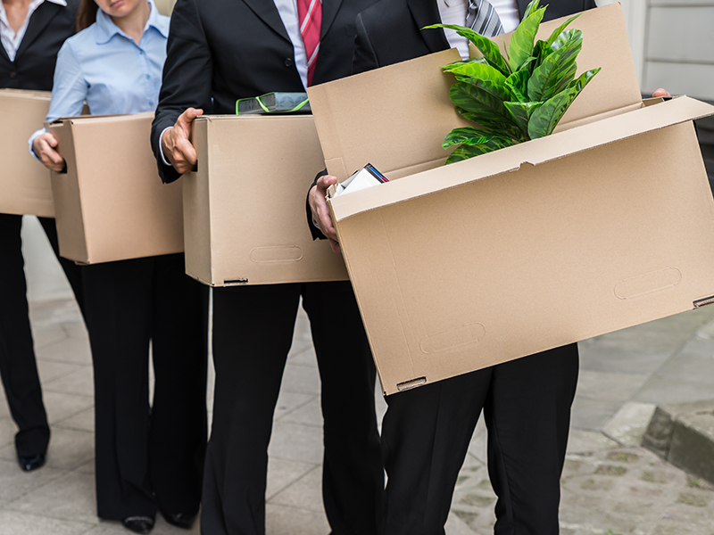 Close-up Of Unemployed Businesspeople Carrying Cardboard Boxes