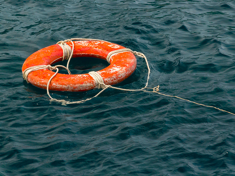 Safe water support aid circle with rope. Rescue red life buoy on wooden background of ship or boat. Helpful object.