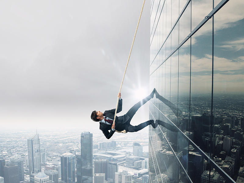Concept of competition with businessman climbing office building with rope