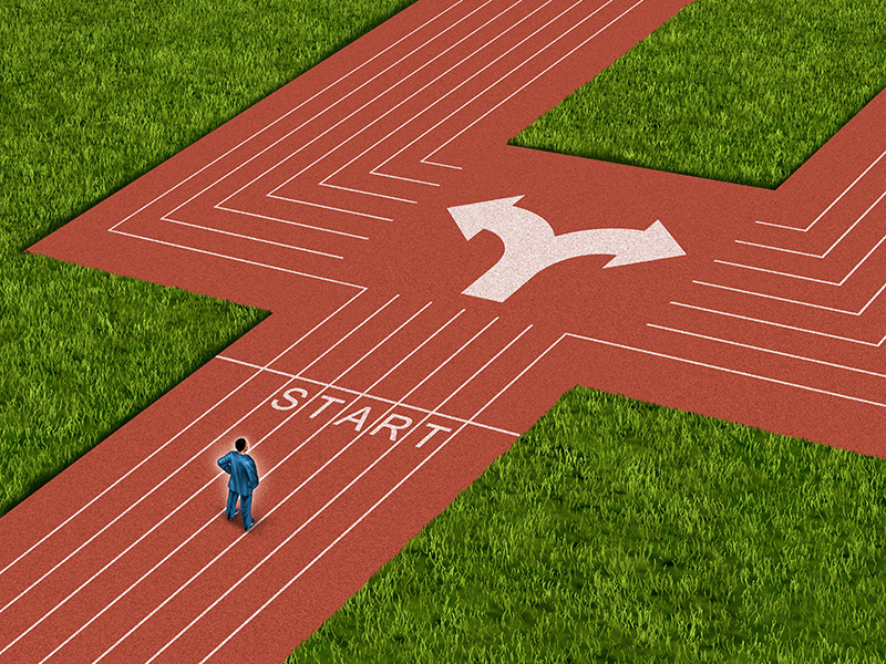 Businessman crossroads concept choosing the right path as a man on a track and field sport track facing a difficult choice and dilemma with two different business directions as a metaphor for decision crisis