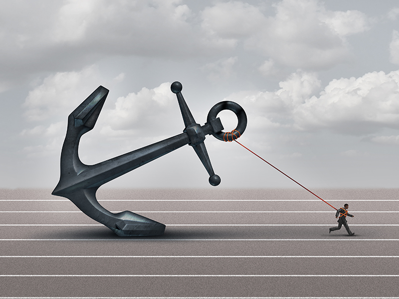 Career burden and business stress concept as a businessman or worker pulling a giant heavy metal anchor as a metaphor for hardship and strugge with taxes or oppression.