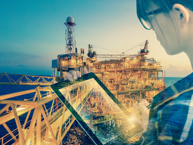 Double exposure of businesswoman in hipster shirt and wearing glasses working with tablet and oil and gas refinery industry plant in the night as Energy and Technology concept