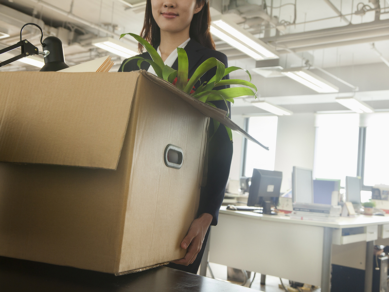young businesswoman moving box with office supplies