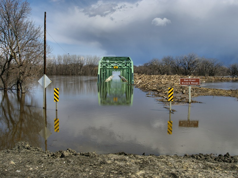 View of a flooded bridge along the Red River. Photograph taken from clay dike