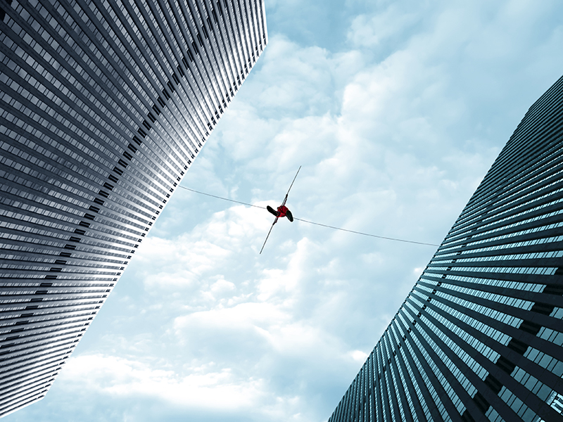 Highline walker in blue sky between two buildings concept of risk taking and challenge