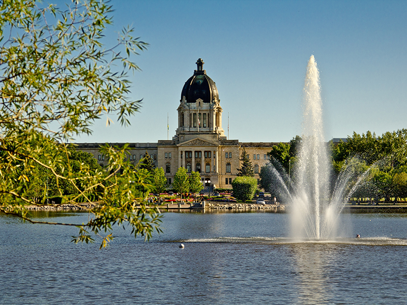 The Saskatchewan Legistlative building in the background and a fountain on Wascana lake on a lovely summer day in Regina.