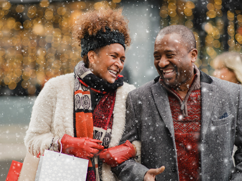 Older couple smiling at each other, with snow in the air