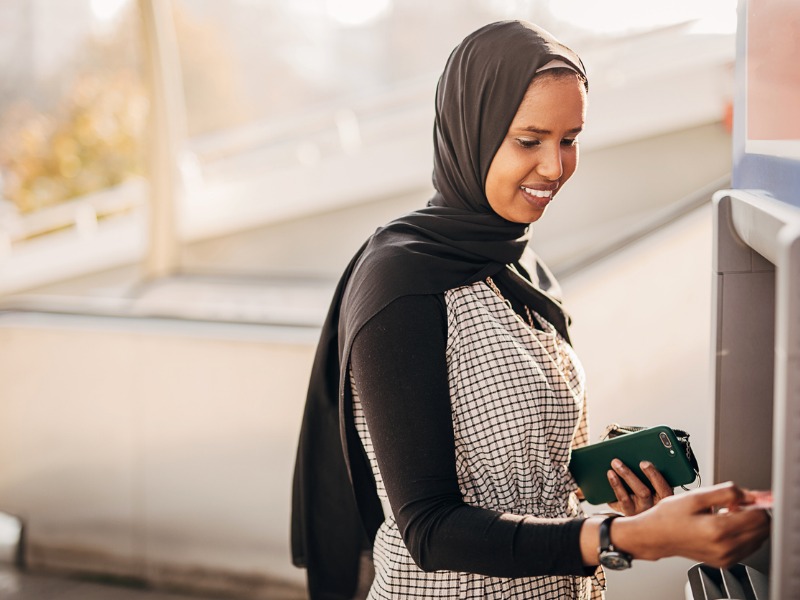 Modern woman with hijab using ATM machine stock photo