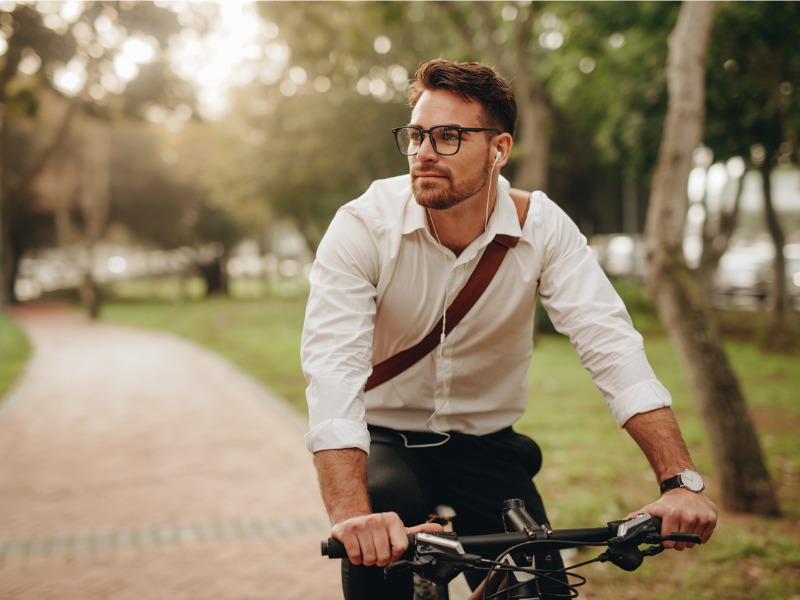 A man enjoying music using earphones while commuting to office on a bicycle.