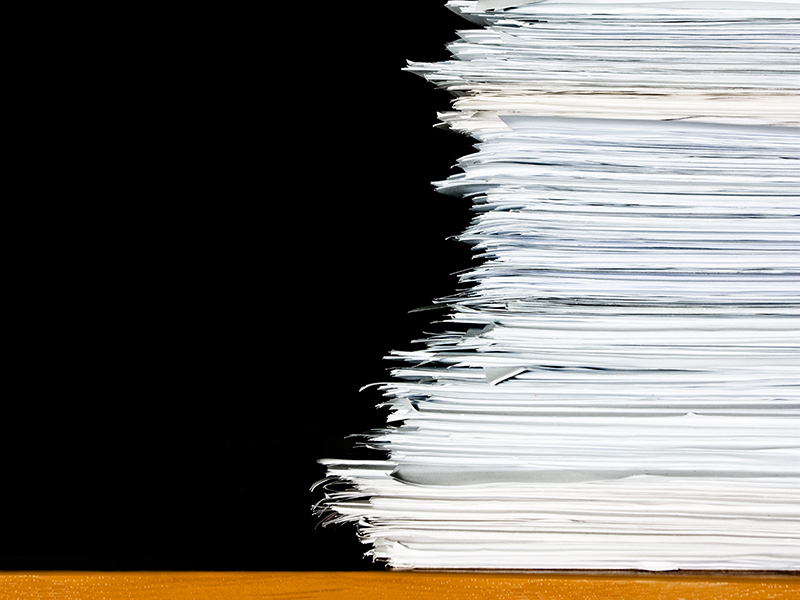 stack of documents or files, overload of paperwork on black background