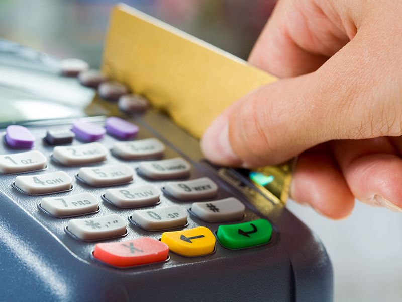 Close-up of payment machine buttons with human hand holding plastic card near by