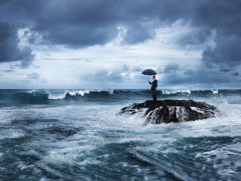 Man stranded on rock in stormy ocean