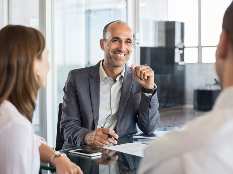 Financial agent in meeting with young couple around boardroom table