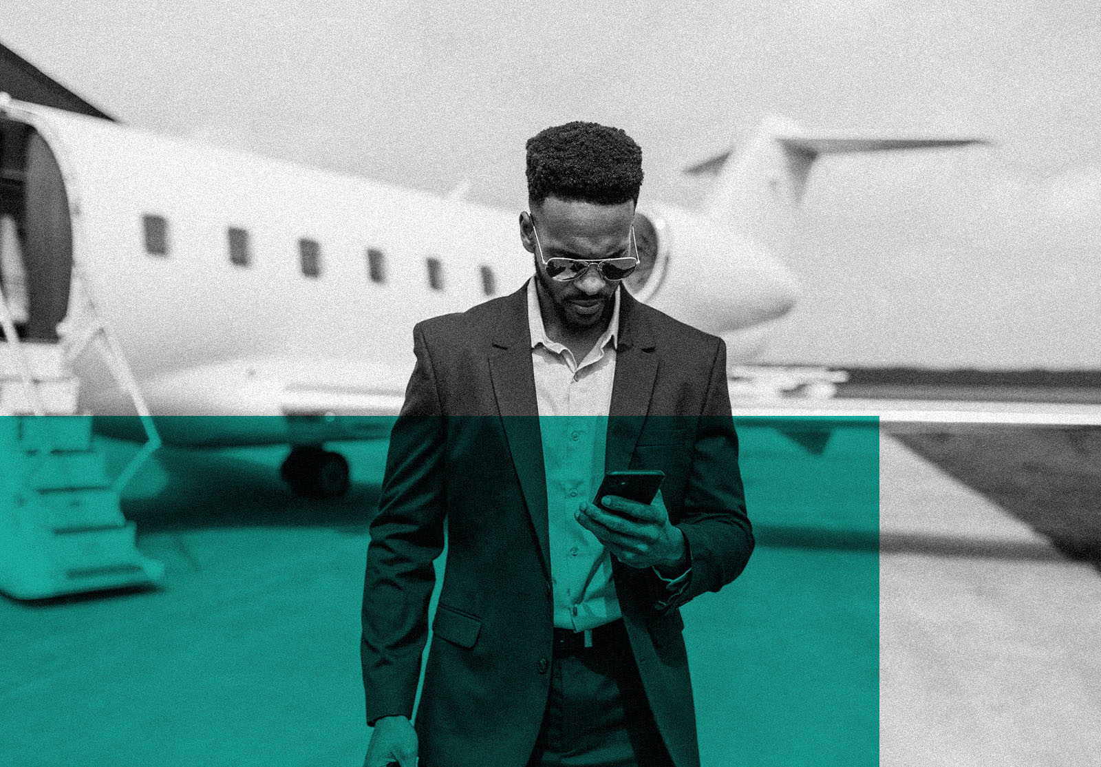 African American entrepreneur traveling by private jet, and using smart phone before boarding